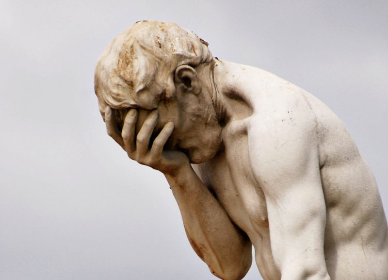 Statua di un uomo con la testa tra le mani