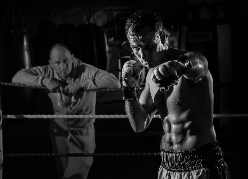 Pugile che si allena sul ring con allenatore che osserva