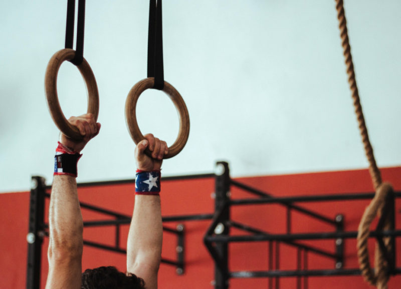 Mani di un atleta che impungano gli anelli per fare muscle-up